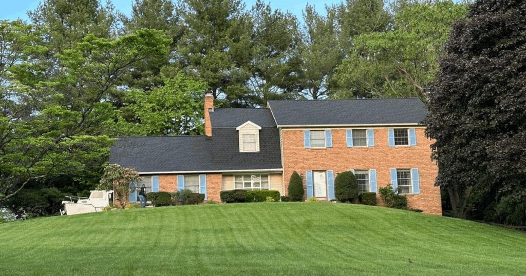 A beautiful Maryland brick home with a newly installed, healthy architectural shingle roof, demonstrating a fully protected building envelope after winter damage restoration.
