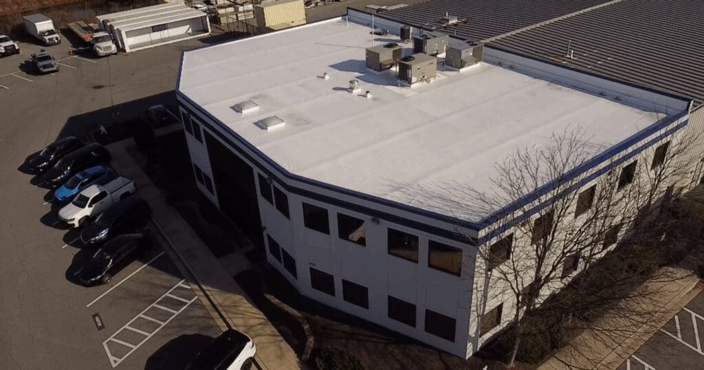An aerial drone photograph of a recently completed, clean white TPO commercial flat roof near Baltimore, illustrating the quality workmanship of local vs. corporate roofing companies.