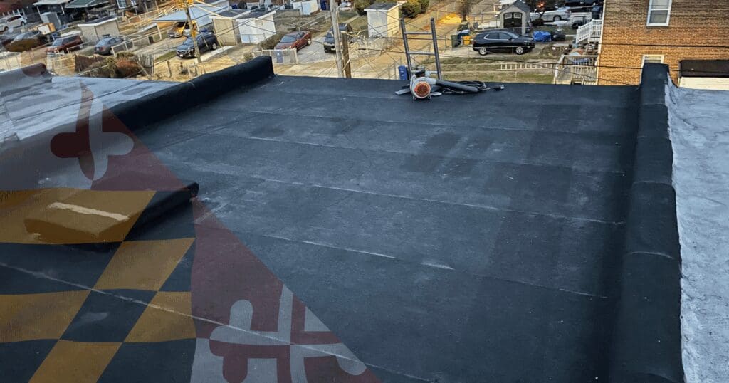 A perspective view across a large, clean dark flat residential roof membrane (Modified Bitumen or B.U.R.). An orange industrial air mover or dryer device sits near the center with wooden access stairs. Penetration flashings and more HVAC equipment are visible. A large Maryland flag watermark is overlaid, representing dedicated residential roof maintenance Baltimore properties require.