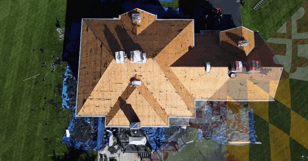 Aerial view of a comprehensive roof tear-off in Baltimore County, exposing the raw OSB plywood decking to execute a rigorous structural audit before installing new underlayment.
