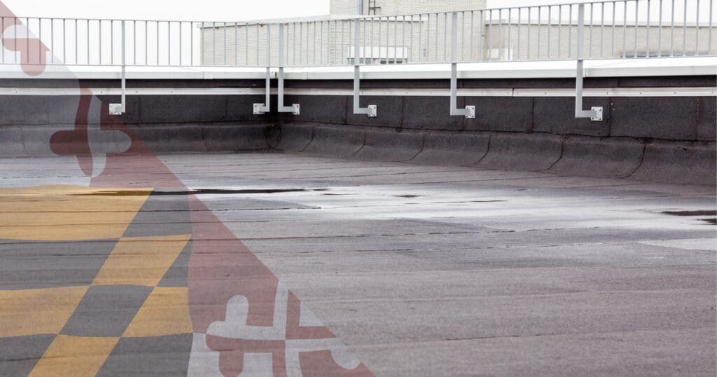 Severe flat roof ponding water collecting on a commercial dark membrane, highlighting the threshold of drainage failure and hydrostatic load.